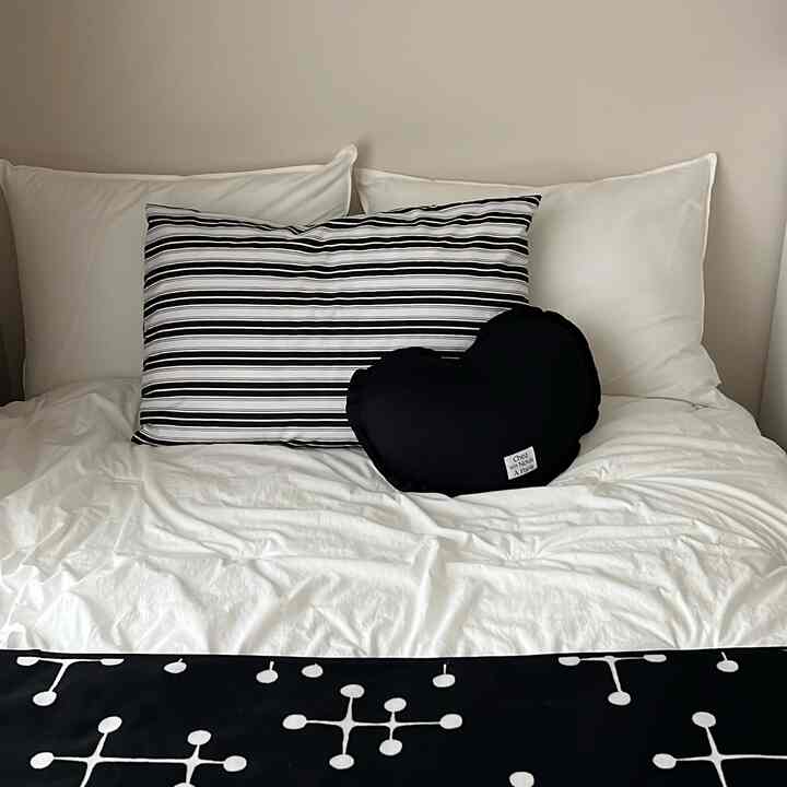 白と黒のトーンの寝室、枕と毛布が整然と配置されたミニマルな雰囲気のインテリア