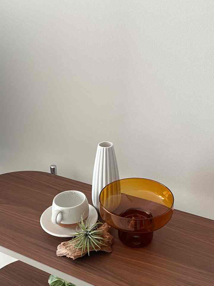 ナチュラルな色調のキッチンスペース、木製の棚の上に白い陶器のティーカップとオイルバーナーが配置された雰囲気のあるインテリア