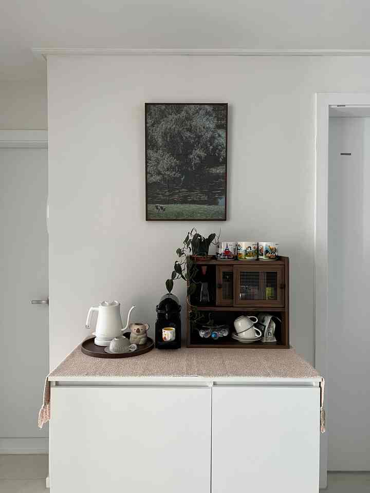 白い壁とキャビネットのキッチンスペース、コーヒーマシンと電気ケトルが置かれた雰囲気のあるおうちカフェコーナー