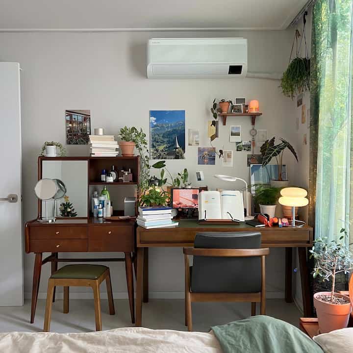 木目調の家具と多くの植物が配置された、居心地の良い書斎兼ホームオフィスの空間