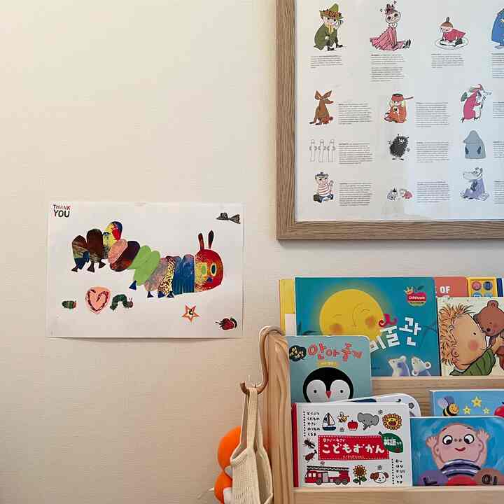 白い壁と木目調の本棚、子供が作った絵とムーミンのポスターがある子供部屋のインテリア