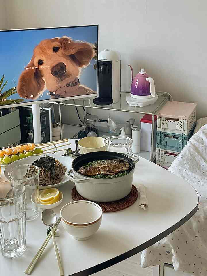 白と茶色のトーンが調和するキッチン、ダイニングテーブルには家庭料理と小型キッチン家電が配置された雰囲気のある空間