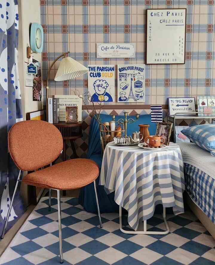 ブルーとイエローのトーンが調和したカフェ風のリビング、オレンジのチェアとフロアランプが温かみのある居心地の良い空間を演出している。