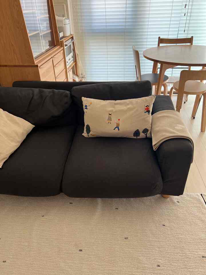 ウッドトーンとブラックのソファが配置されたナチュラルスタイルのリビングとダイニングルームの空間