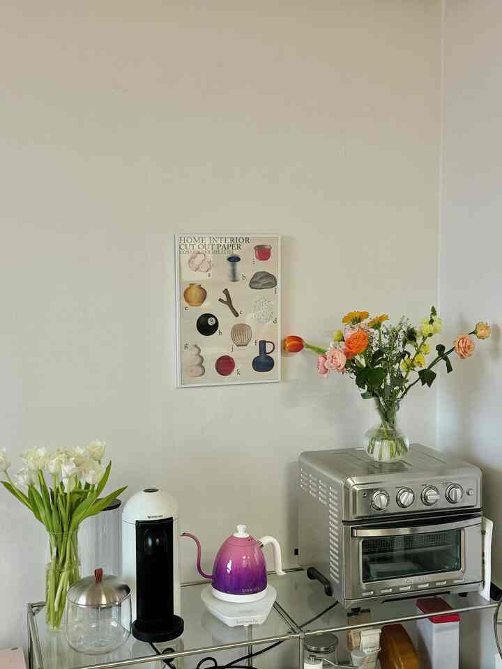 白い壁と透明なガラス棚にモダンなキッチン家電と花瓶が置かれたキッチンコーナー