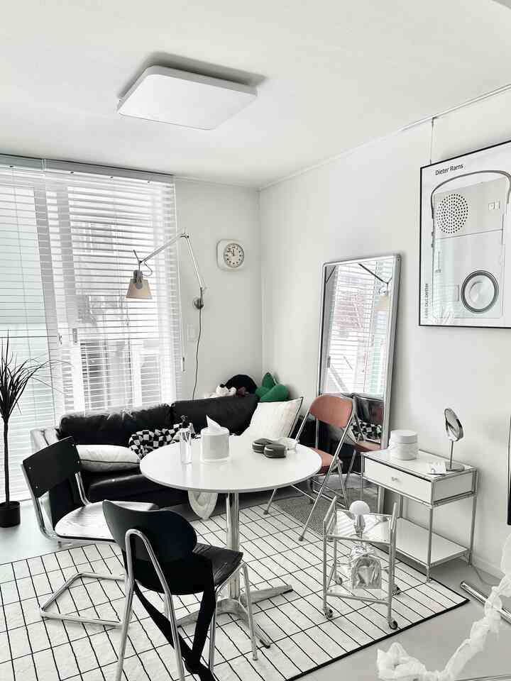 白い壁と床に黒い家具が調和するモダンなリビング、丸テーブルと個性的なレイアウトが印象的な空間