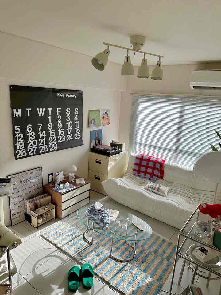 白とライトブラウンの色調のリビングルーム、白いソファとストライプのラグが配置されたモダンなインテリア