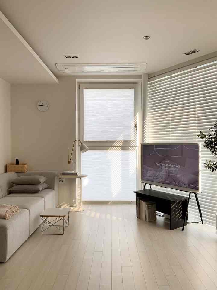 明るい木目調の床と白い壁のリビング、グレーのソファとサムスンセリフテレビが配置されたナチュラルモダンなインテリア