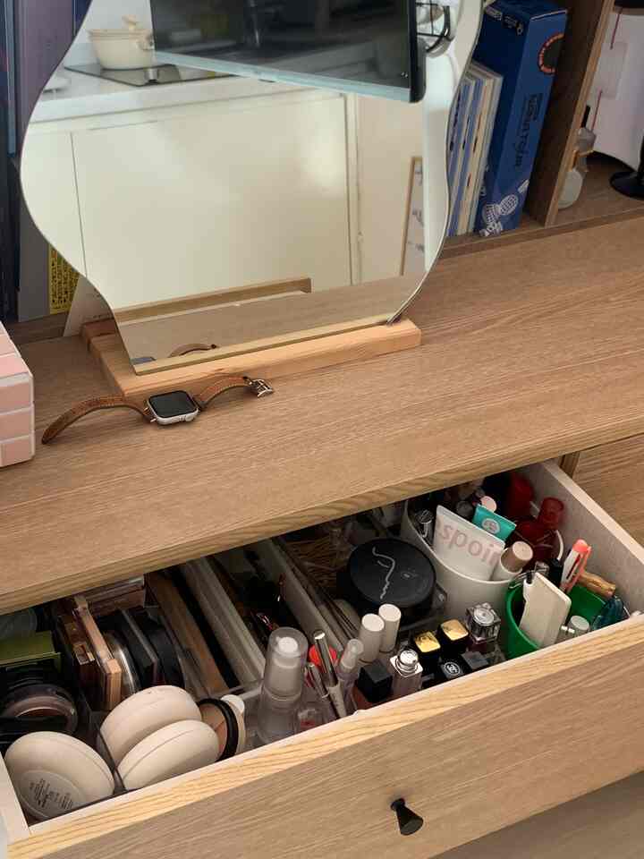 ナチュラルな木目調の化粧台と鏡、化粧品が収納された引き出しが開いた清潔なメイクスペース
