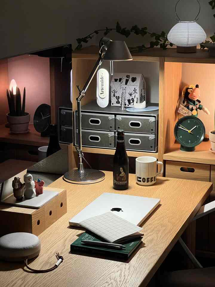 ナチュラルカラーのホームオフィス、木製デスクとチェスト、テーブルランプと時計が配置されたシンプルで整った作業空間