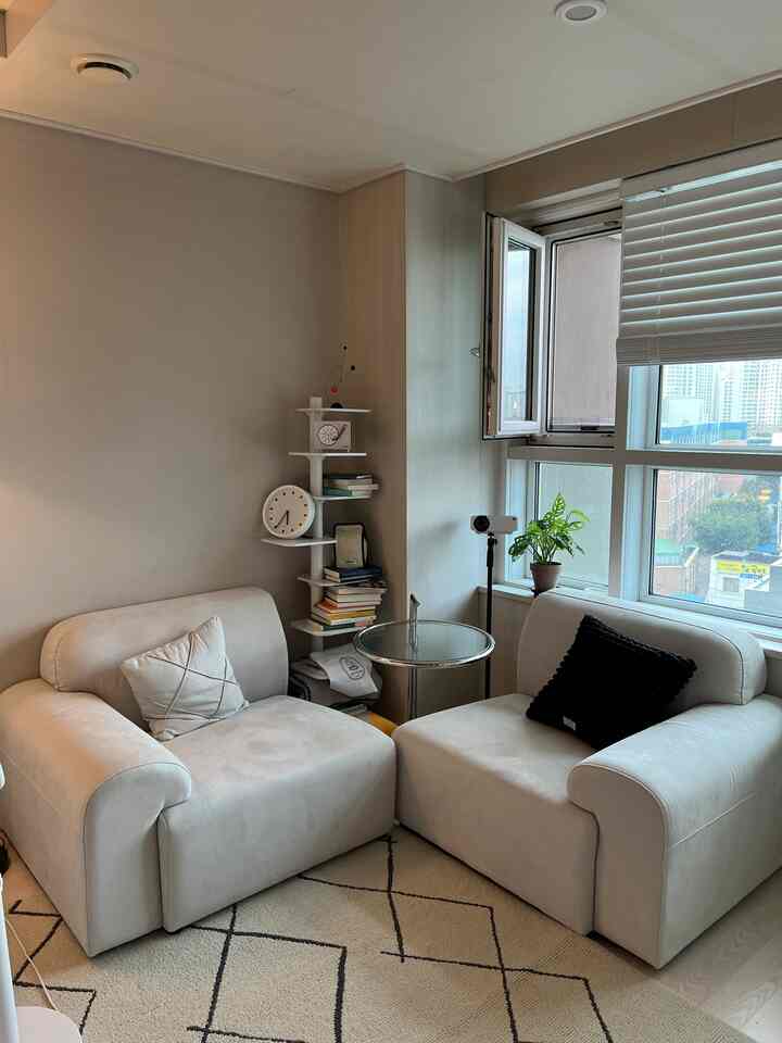 ベージュの落ち着いたリビング、モダンなソファ2台と丸いサイドテーブル、ラグが温かみのある雰囲気のあるインテリア