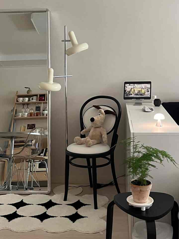 ホワイトとブラックの色調のリビング兼寝室空間、収納キャビネットとモダン家具が配置された印象的なインテリア