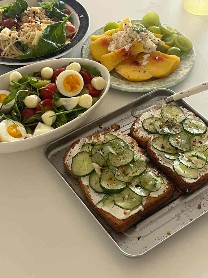 白いテーブルの上に茶色のトーストと新鮮なサラダ、桃、ブドウが並んだ清潔感ある朝食のテーブルセッティング