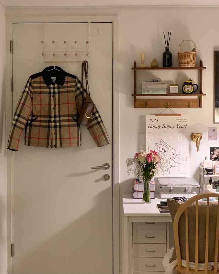 白と木目調が調和した玄関のコートハンガーと棚が配置された温かみのある作業空間