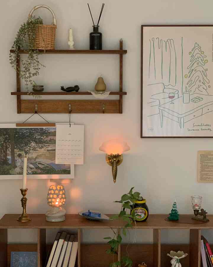 ナチュラルトーンの壁に木製の棚、額縁、ディフューザーが配された雰囲気あるインテリア