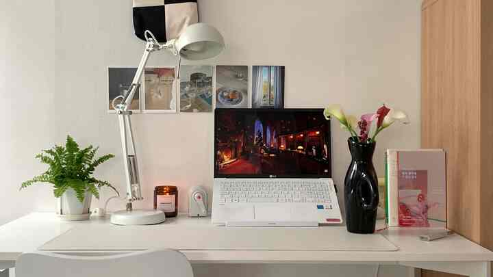 ミニマルな白を基調としたホームオフィス空間、机の上にノートパソコンと花瓶などが整然と配置された雰囲気のあるインテリア