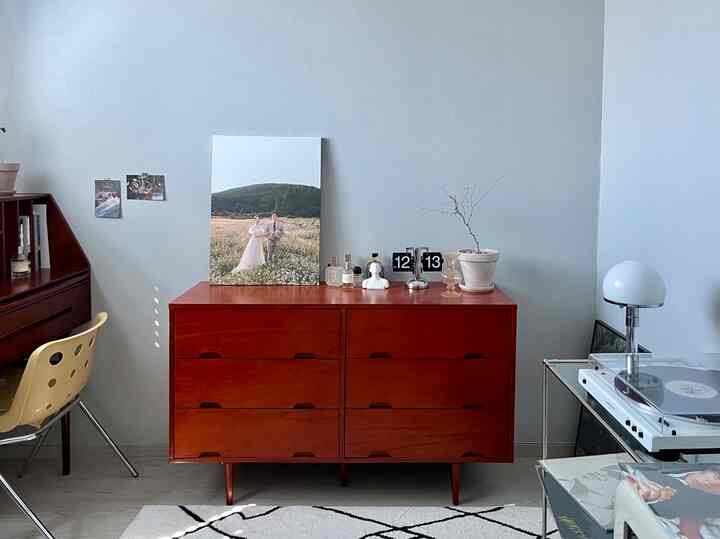 淡いグレーの壁に濃い木目調のチェストとターンテーブルが配置されたミッドセンチュリーモダンのホームオフィス風インテリア