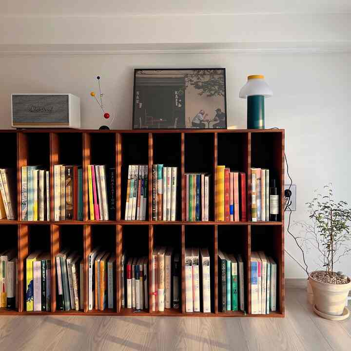 白い壁と低い天井の下に配置されたブラウンの本棚、本やオブジェが並ぶナチュラルな雰囲気のインテリア