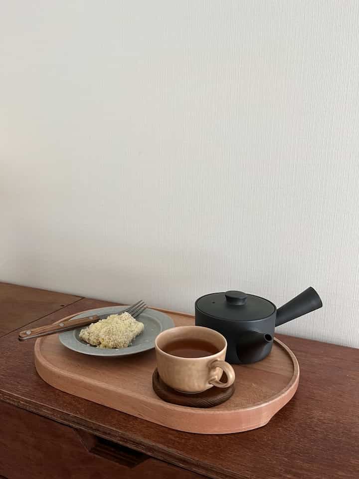 ナチュラルな木目調のトレイにティーカップとお茶セットが配置されたシンプルなキッチンスペース