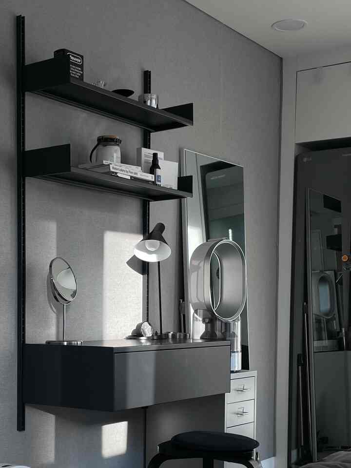 チャコールとブラックのトーンのモダンな部屋、壁棚と大きな全身鏡、化粧台とスツールが配置された洗練された空間