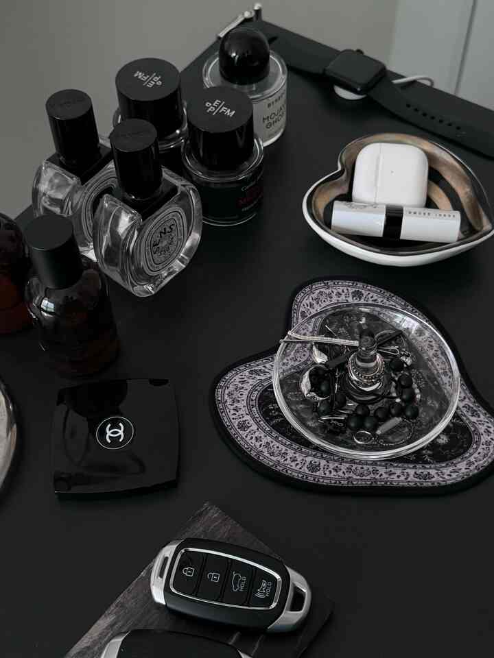 ダークトーンの玄関棚に香水ボトル、エアポッド、アクセサリーが整然と配置されたモダンなインテリア