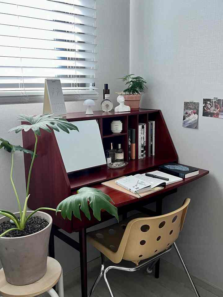 自然光が差し込むナチュラルな木目調のデスクとベージュの椅子が配された清潔感のあるホームオフィス