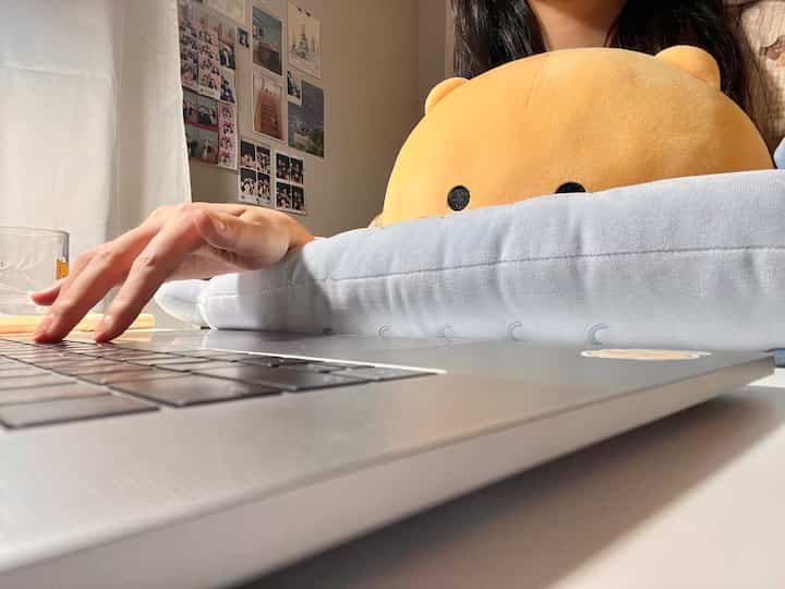 白と茶色のトーンが特徴のホームオフィス、ノートパソコンと可愛いリストレストクッションが置かれた落ち着いたデスク空間