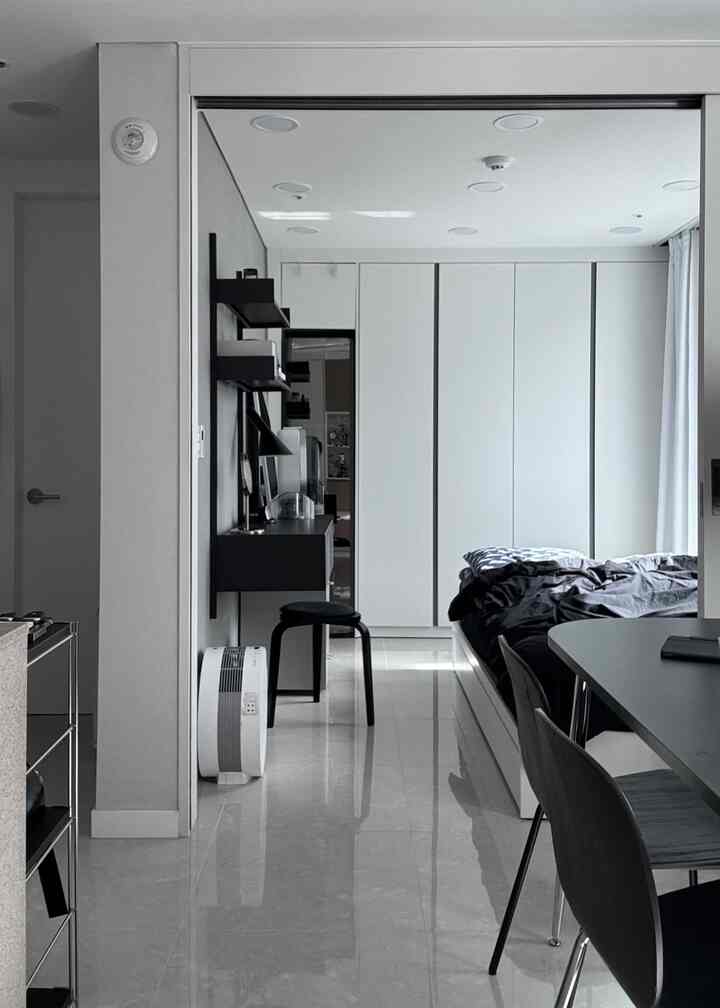 白と黒のモダンな寝室、壁掛け棚とミニマルな家具が配置された印象的な空間