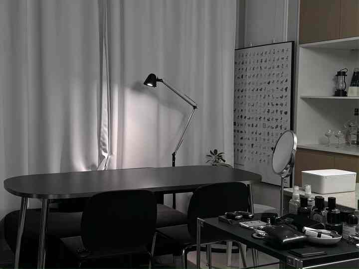 白い壁とカーテンを背景に、黒のダイニングテーブルと椅子、アーティキュレーテッドのフロアランプが配置されたシンプルモダンなダイニングルーム