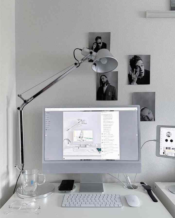 白とシルバーのトーンが調和したシンプルなホームオフィス、パソコンと照明が配置されたすっきりしたデスク