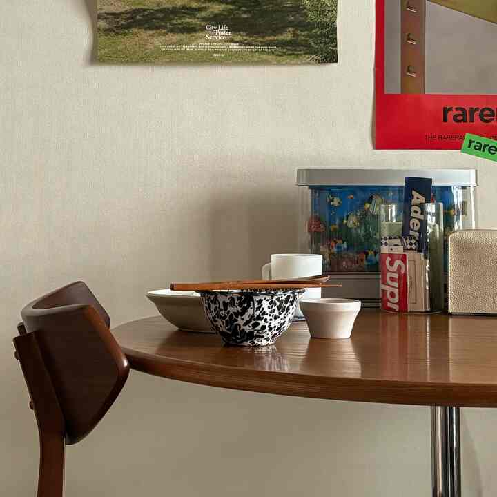 ブラウンの木製ダイニングテーブルと椅子、柄入りとシンプルな食器が配置された雰囲気のある寝室空間