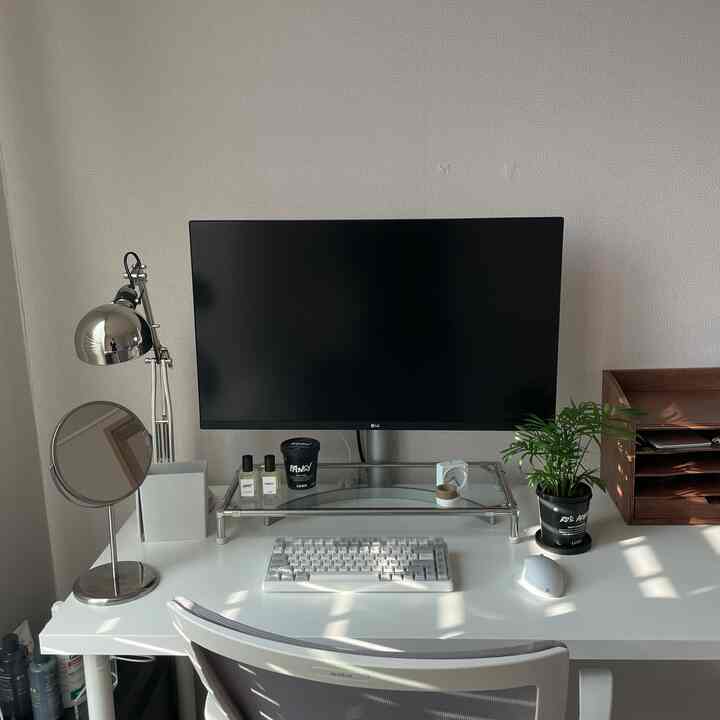 白とシルバーのホームオフィス、清潔なデスクとモニター、植物が配置されたモダンな印象の空間