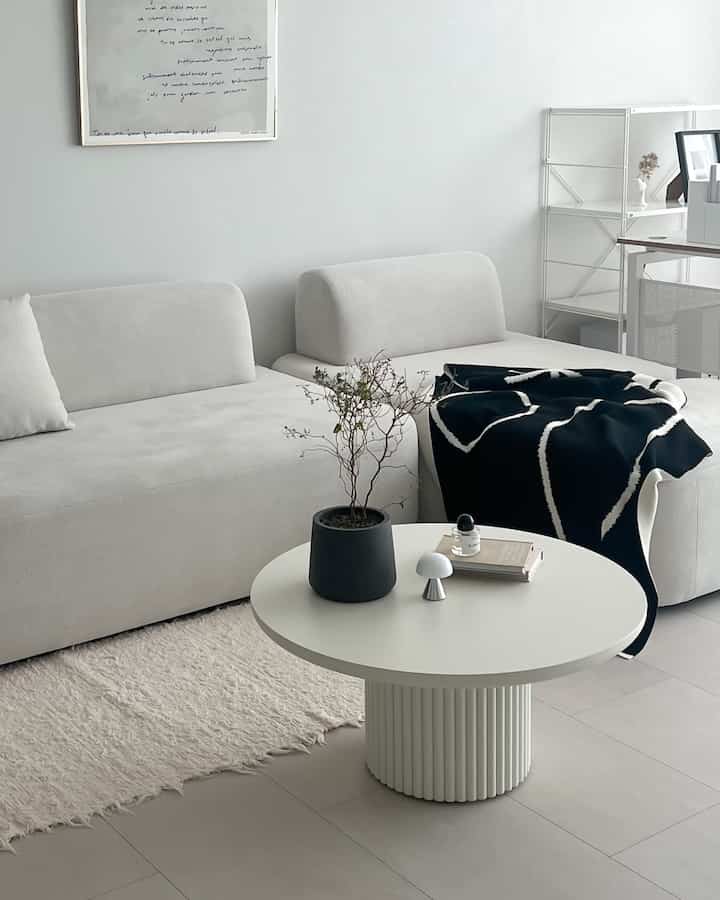 白とグレーの色調のリビング、モダンなソファと丸いコーヒーテーブルが配置されたシンプルでミニマルな印象的な空間