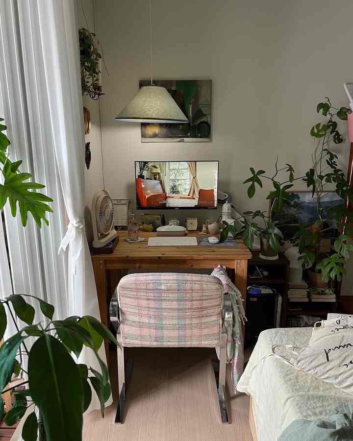 ナチュラルな色調の寝室、ヴィンテージのチェック柄アームチェアと木製デスクが配置された落ち着いたホームオフィス環境