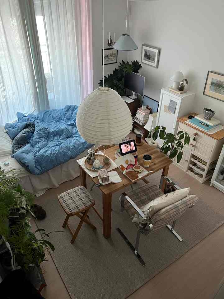 ナチュラルカラーのワンルーム、ダイニングテーブルを机として使い、チェック柄のビンテージスツールが配された雰囲気のあるインテリア