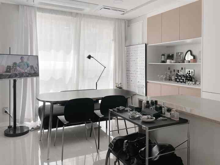 白と黒のトーンのダイニングルーム、シンプルなテーブルと椅子、明るいカーテンと収納が調和した雰囲気のあるインテリア