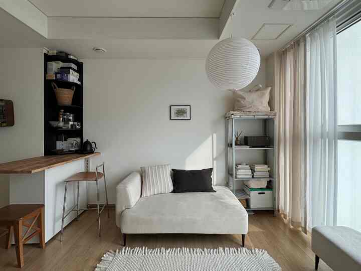 白と木目調のリビング、ソファとバーテーブルが配置された清潔感のあるナチュラルな空間