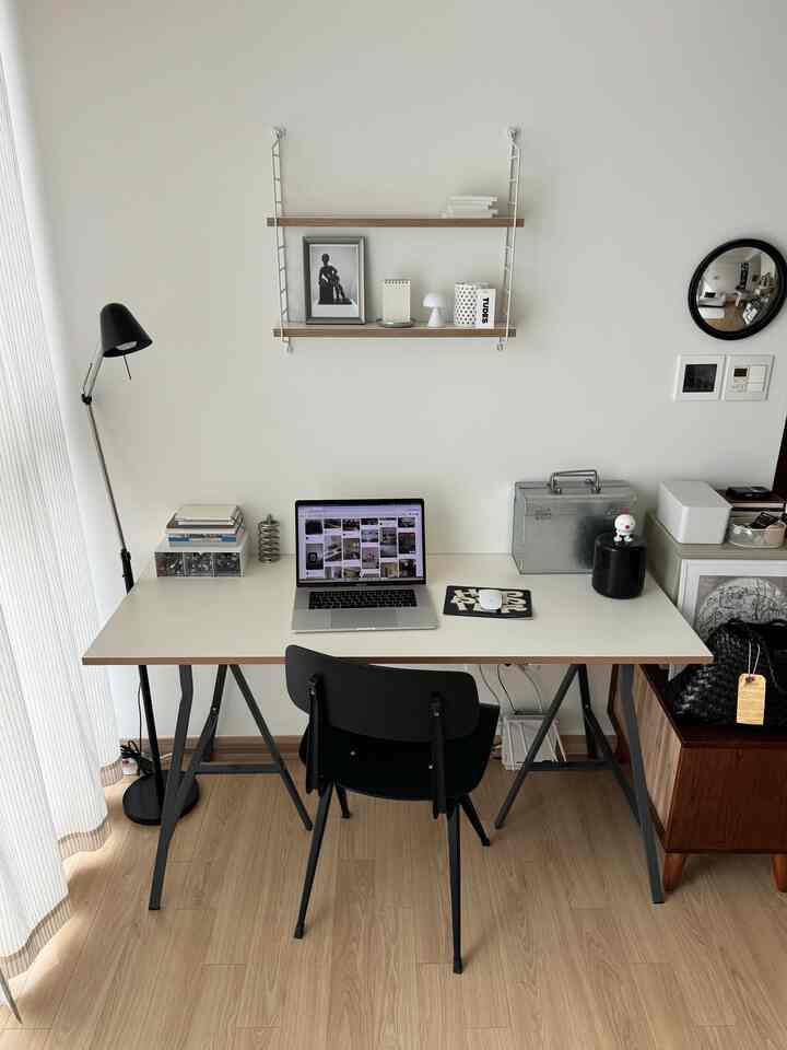 ナチュラルカラーの白い壁のホームオフィス、シンプルなデスクと黒のオフィスチェアが配置された落ち着いた作業空間