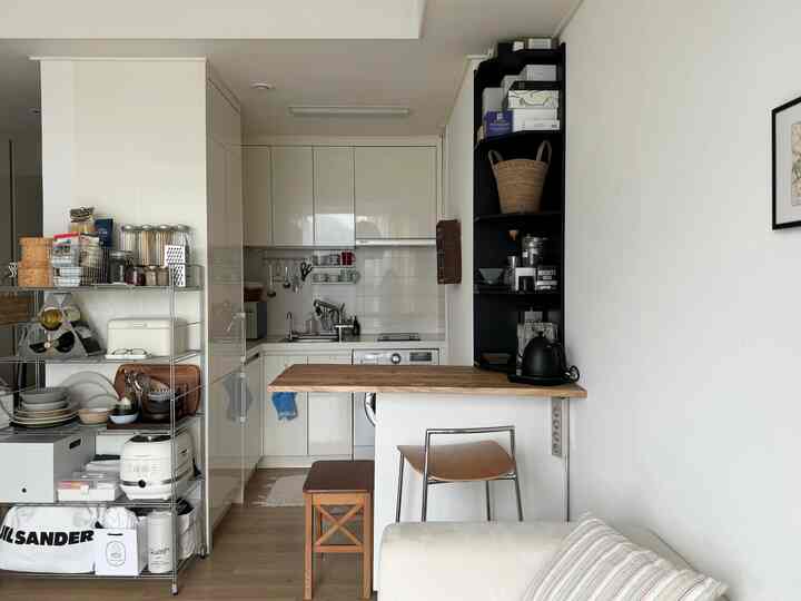 ホワイトと木目調の調和が取れた小さなコの字型キッチンとリビング、実用的なコーナー収納とバー付きのモダンなインテリア