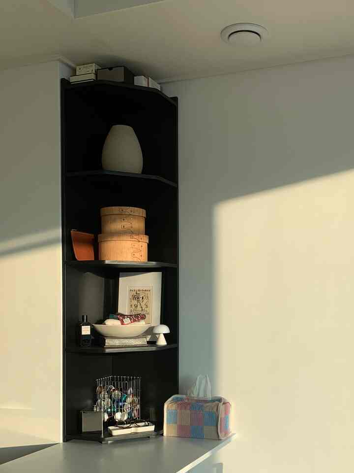 白い壁と黒いコーナーシェルフが配置されたシンプルで整った空間