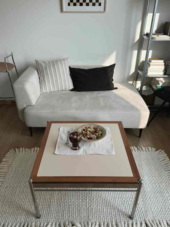 ホワイトとブラウンのトーンが印象的な狭いリビング、モダンなソファとコーヒーテーブルが配置された空間