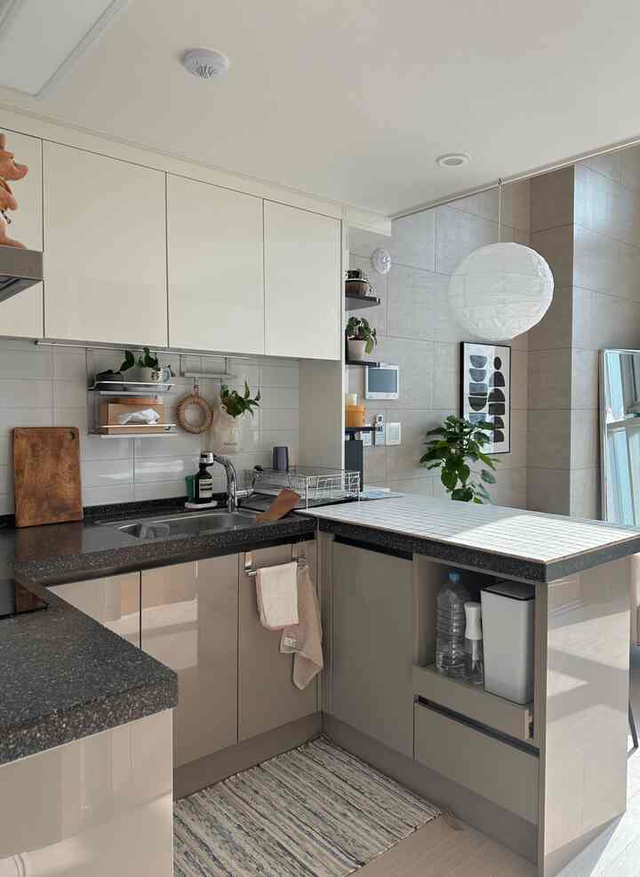 ナチュラルトーンのキッチンスペース、白い吊り戸棚とブラウンの下部収納、ペンダントライトがあるすっきりとしたモダンなインテリア