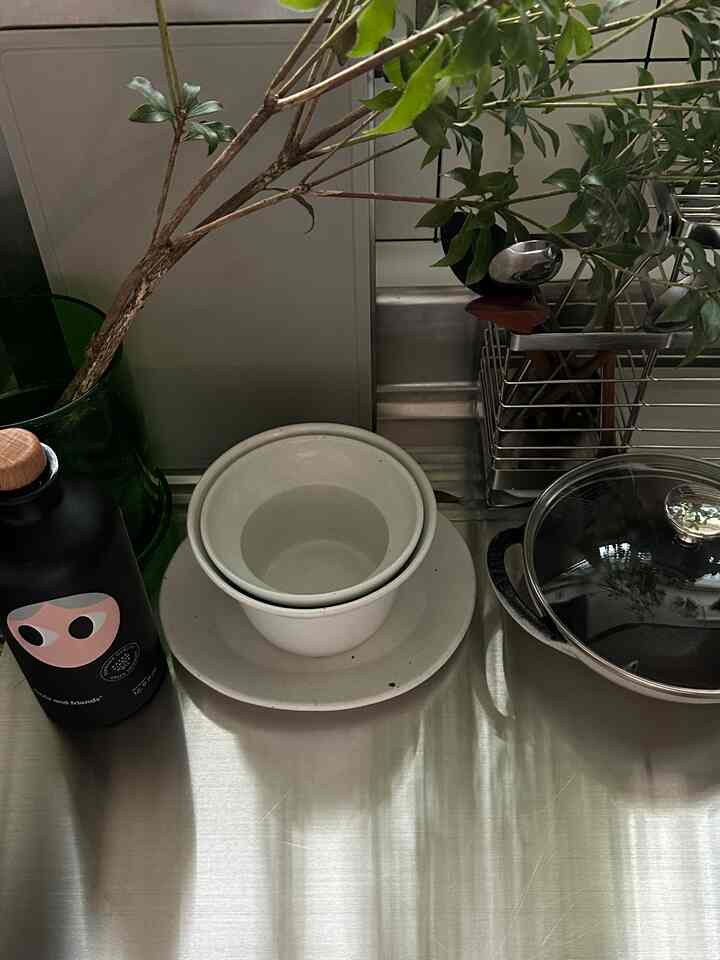 グレーのキッチン調理台、ステンレス天板と整理された食器や調理器具が置かれた雰囲気のあるインテリア