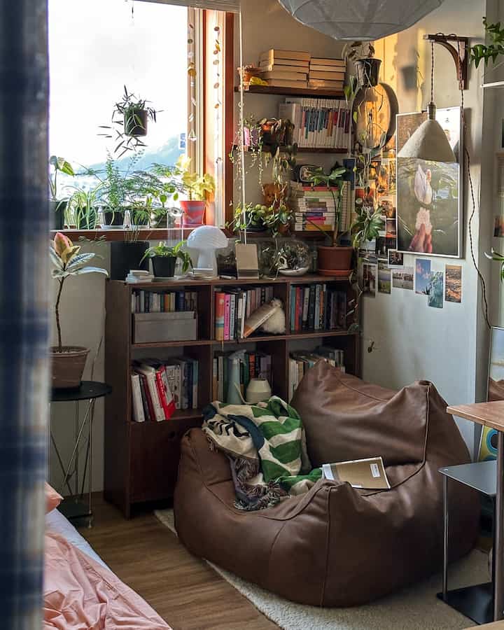 ナチュラルな木目調と緑の植物が調和するコンパクトな書斎スペース、ビーズクッションと本棚が配置された居心地の良い読書空間