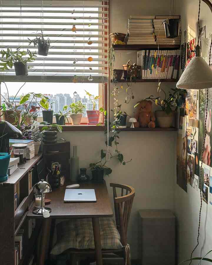自然な色調の狭いホームオフィス、ウッドデスクと多様な植物が配置された居心地の良い作業空間