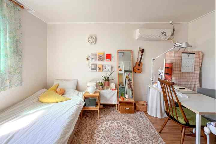 ホワイトと木目調が調和した一人暮らしの寝室、ペルシャ絨毯とヴィンテージフローラルのミントカーテンが印象的な雰囲気のあるインテリア