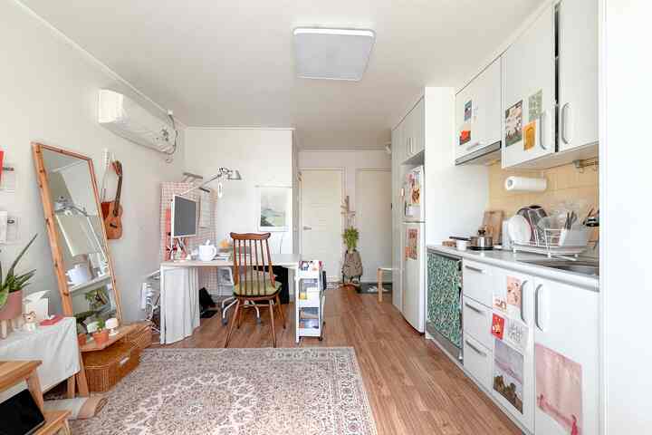 白とブラウンの木目調が調和する一人暮らし向けの狭い部屋、ホームオフィスとキッチンを兼ねた自然な雰囲気のインテリア