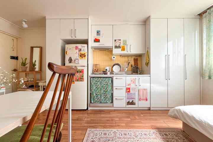 ホワイトとウッドトーンが調和したワンルームのキッチンと寝室が一体となった多機能で温かみのあるインテリア