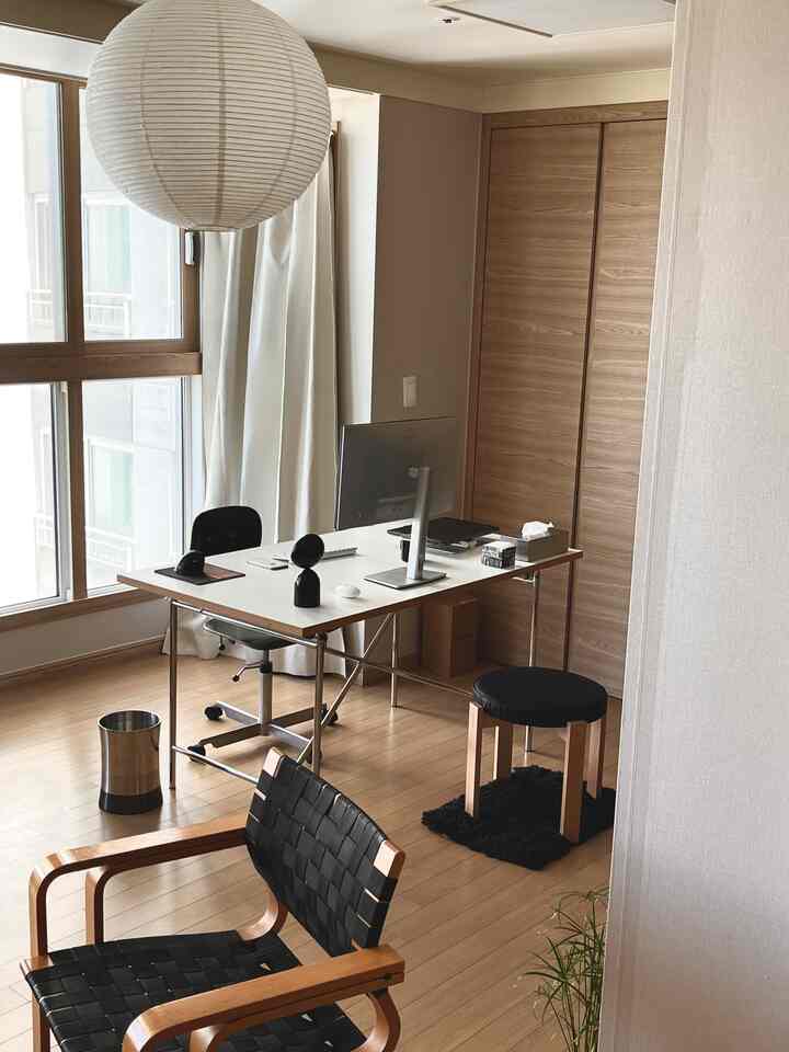 ナチュラルカラーとホワイトのホームオフィス、広いデスクにモニターとデジタル機器が配置された清潔感のある作業空間