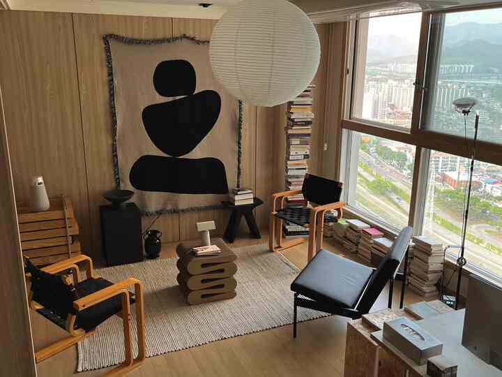 自然な木目調と黒のアクセントが調和した北欧風リビング、大きな窓と読書スペースのある落ち着いたインテリア